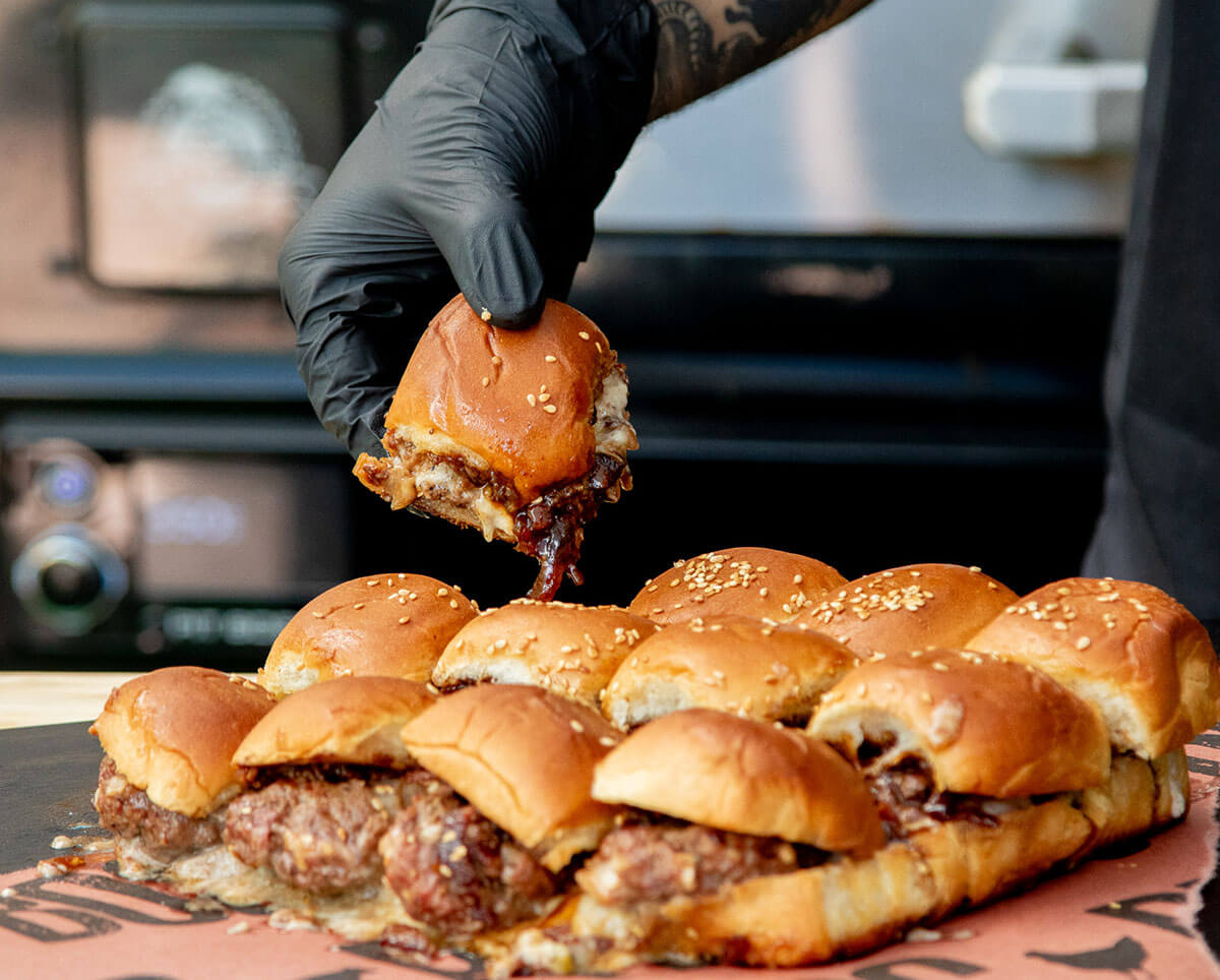 Cheeseburger sliders topped with caramelized onion bacon jam with fresh jalapeno aioli on Hawaiian rolls