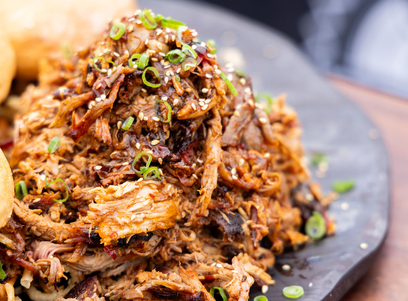 Smoked and Braised BBQ Pulled Pork flavored with chili garlic and topped with sliced green onions