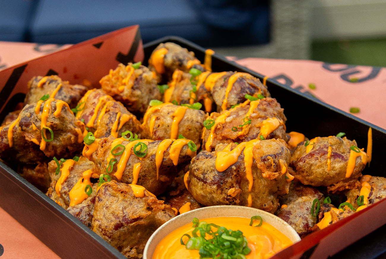 Crispy pork burnt ends topped with creamy buffalo cream cheese sauce drizzle and green onions