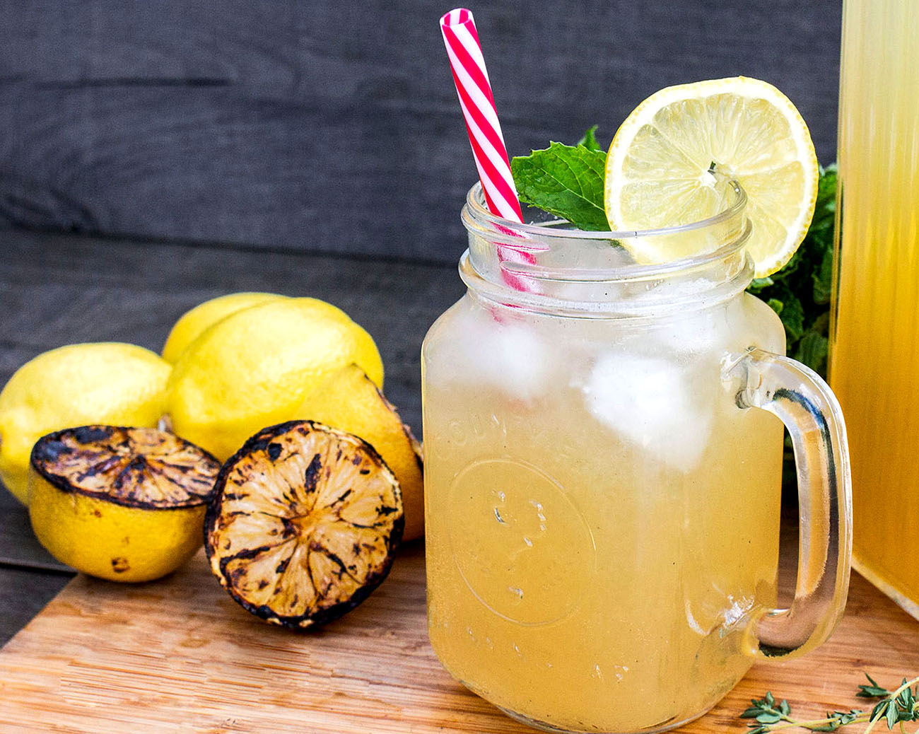 a refreshing smoked lemonade over ice with charred lemons in a mason jar glass